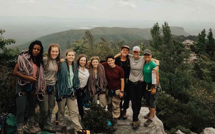 a group of students pose atop a summit in the blue ridge mountains on an outward bound course